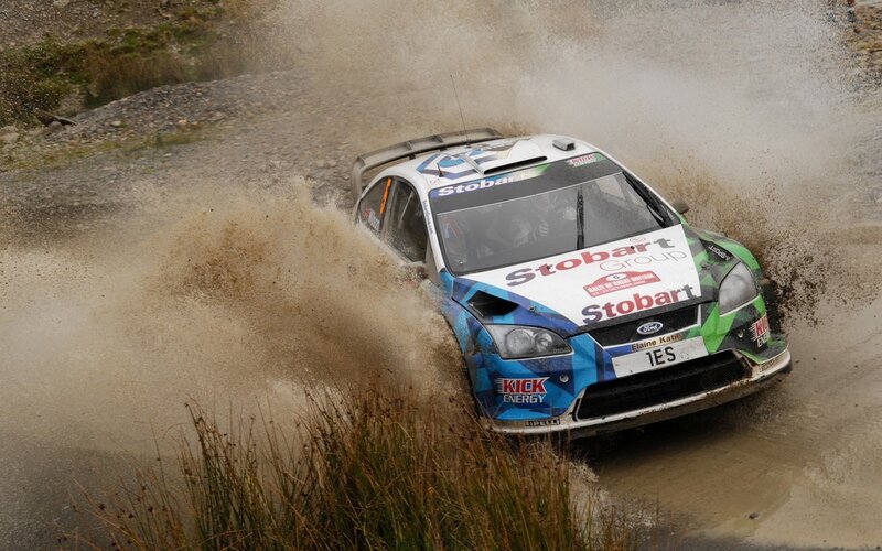 Rally car splashing through mud
