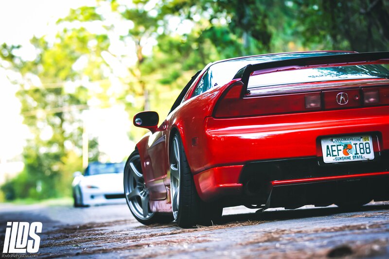 Red Acura NSX on a tree-lined road