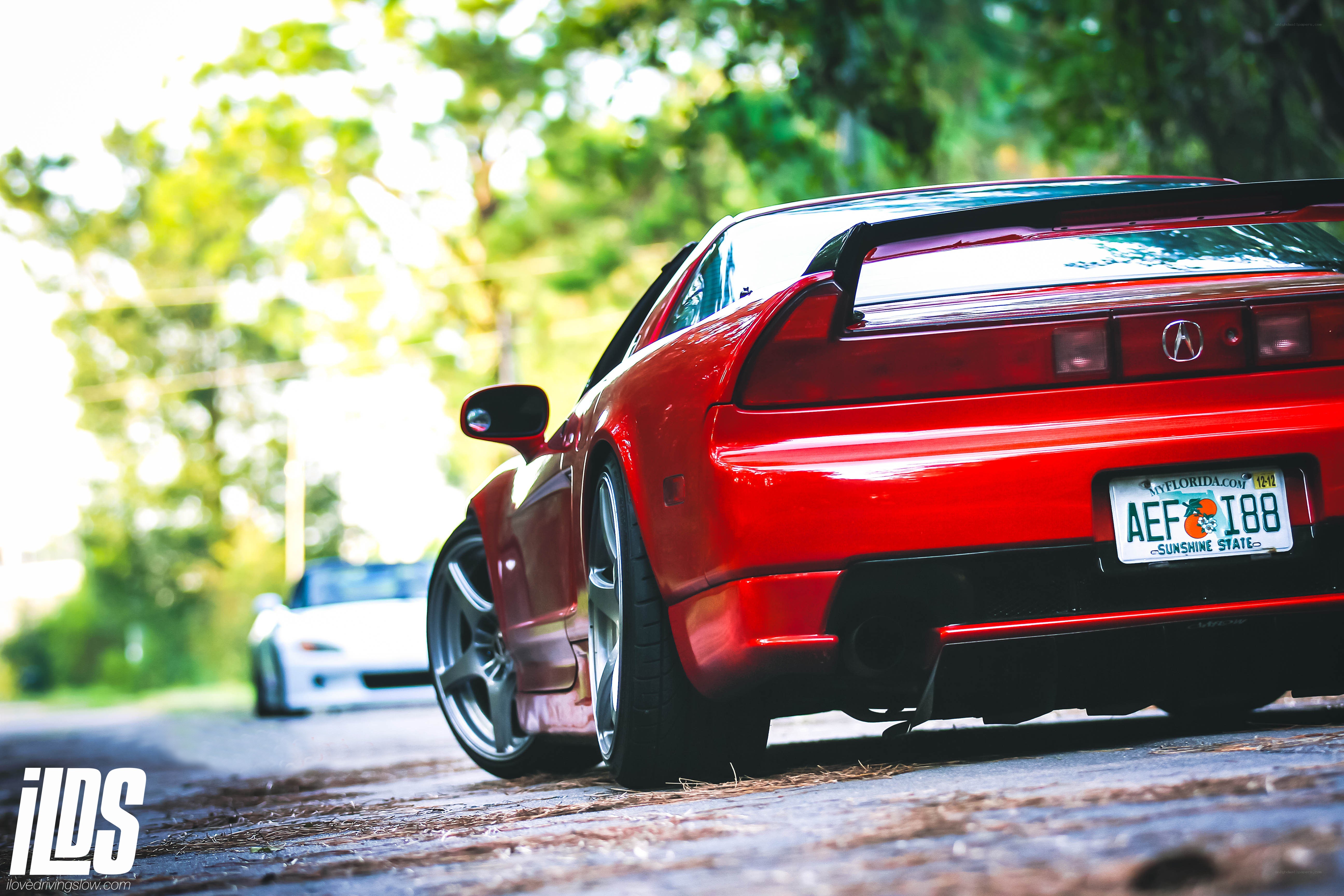 Red Acura NSX on a tree-lined road