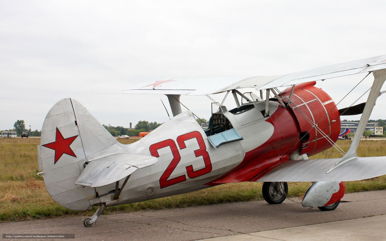 Red and silver biplane on tarmac