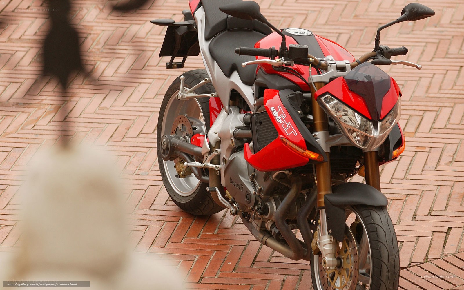 Red and silver motorcycle on brick pavement