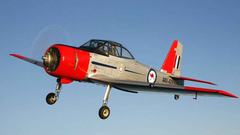 Red and silver training aircraft in flight