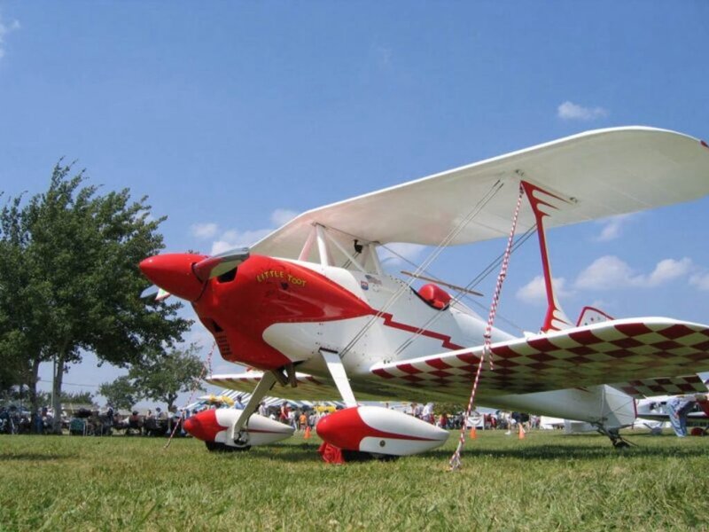 Red and white biplane on grass