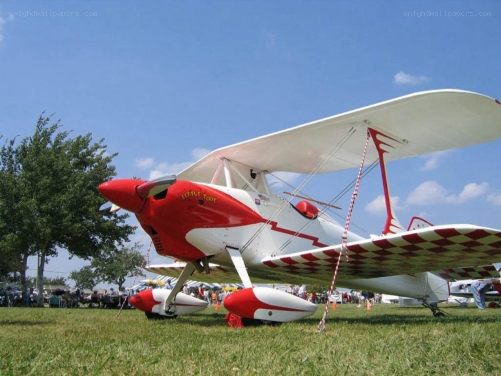 Red and white biplane on grass