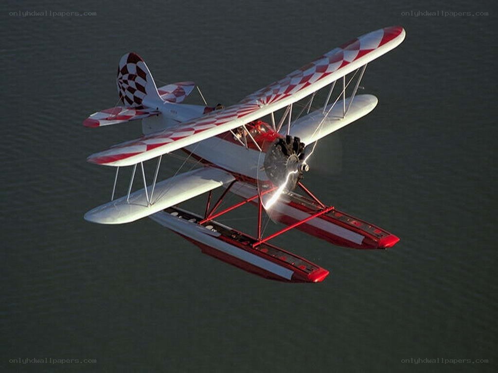 Red and white biplane over water