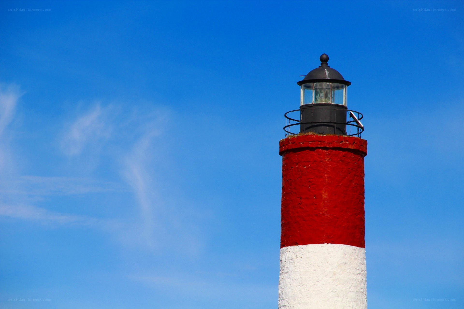 Red and white lighthouse against blue sky
