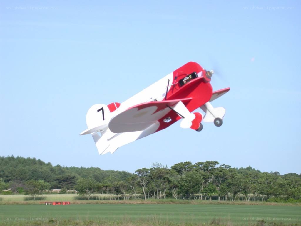 Red and white model airplane in flight