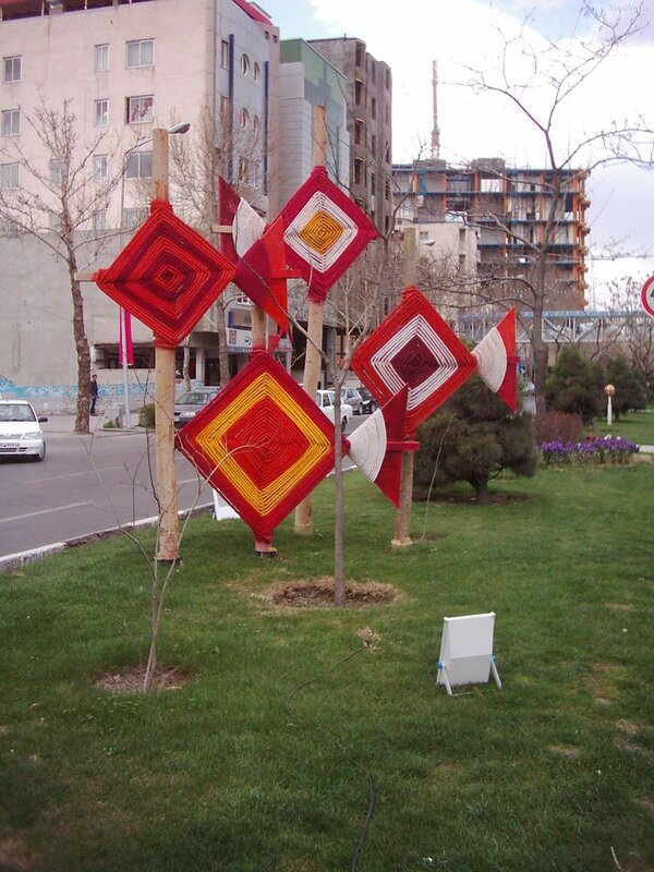 Red and yellow knitted art on poles