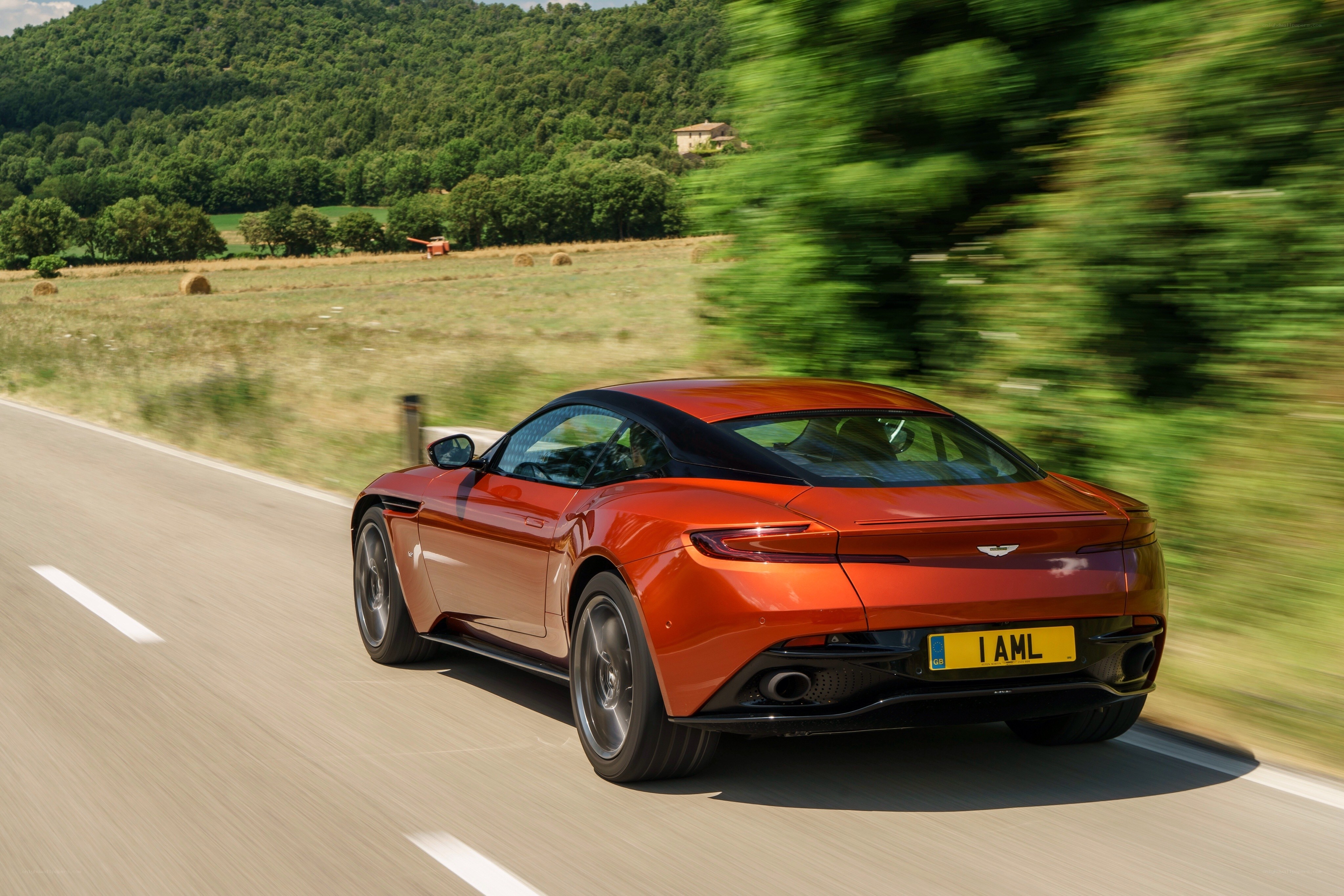 Red Aston Martin driving on country road