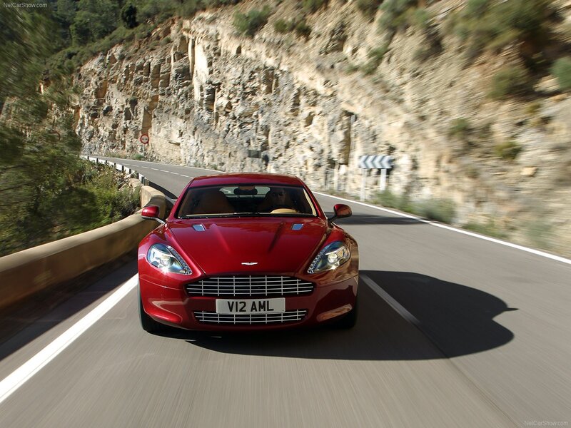 red aston martin driving on mountain road