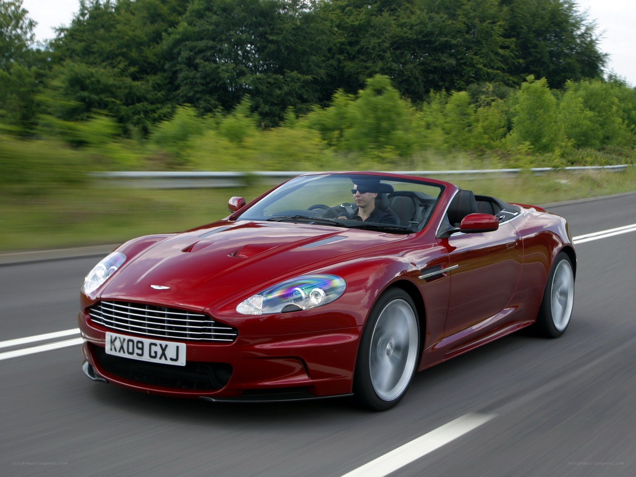 Red Aston Martin driving on road