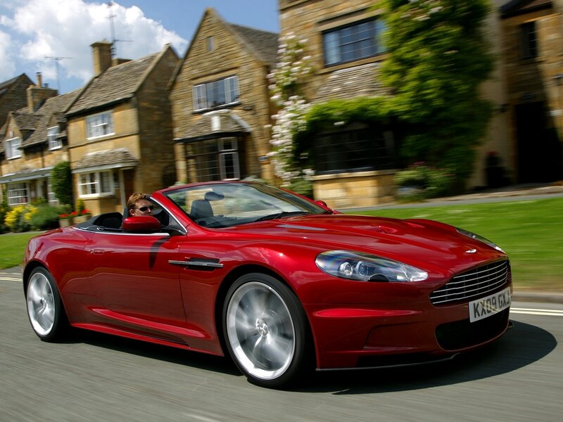 Red Aston Martin driving through village