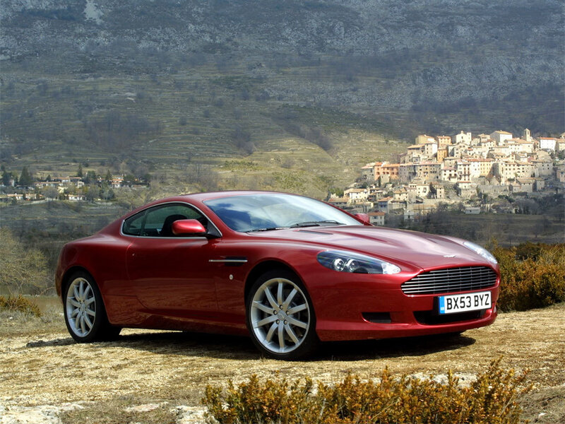 Red Aston Martin in a scenic landscape