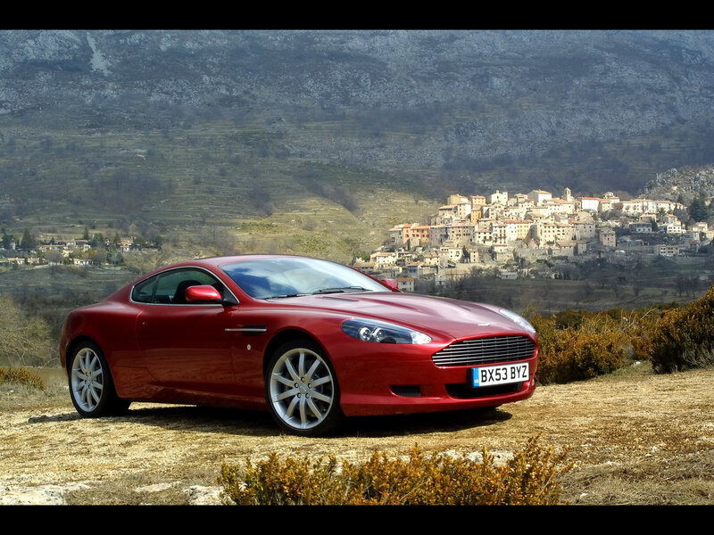 Red Aston Martin in a scenic landscape