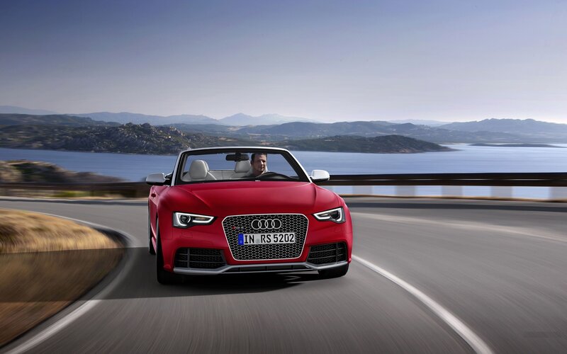 Red Audi RS5 driving on coastal road