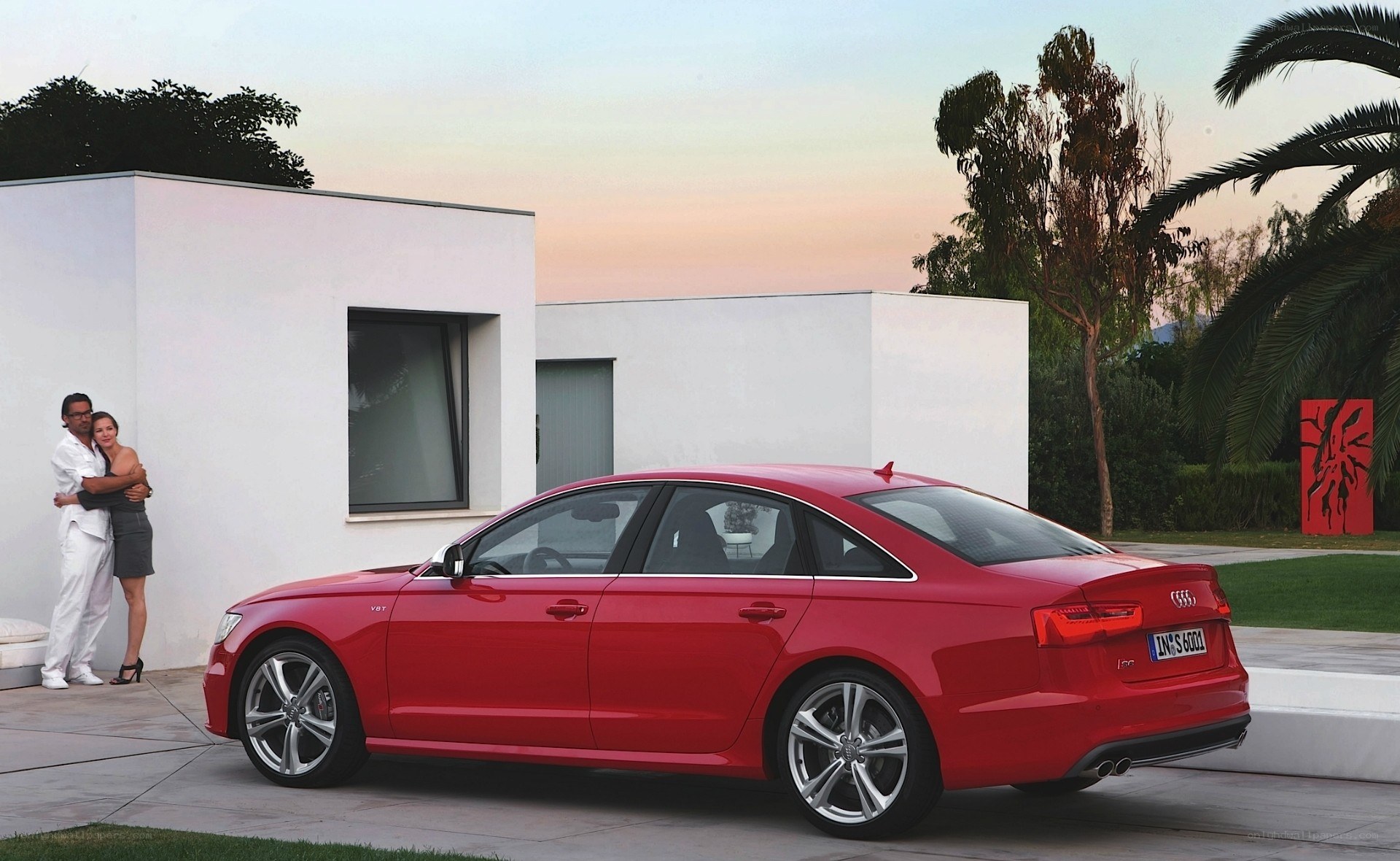 Red Audi sedan by modern house