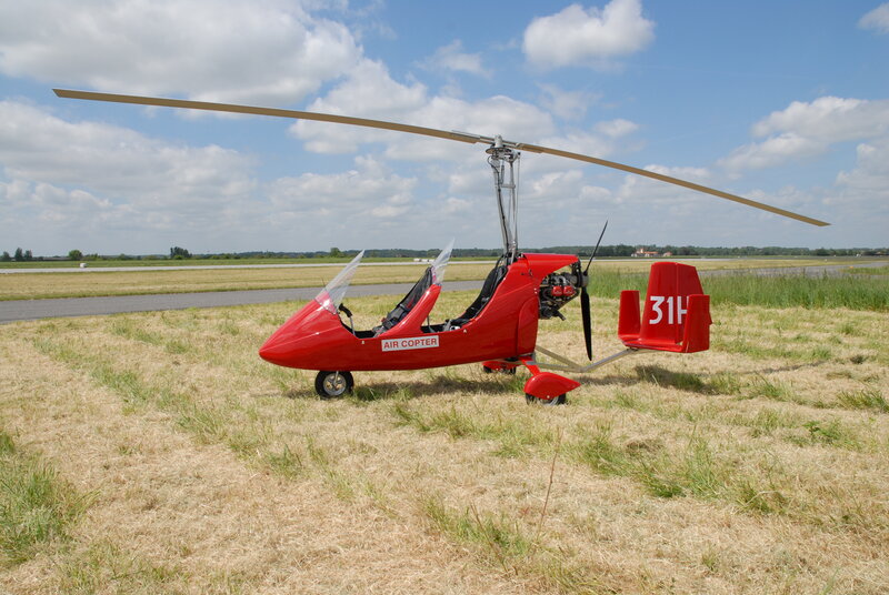 Red autogyro on grass field
