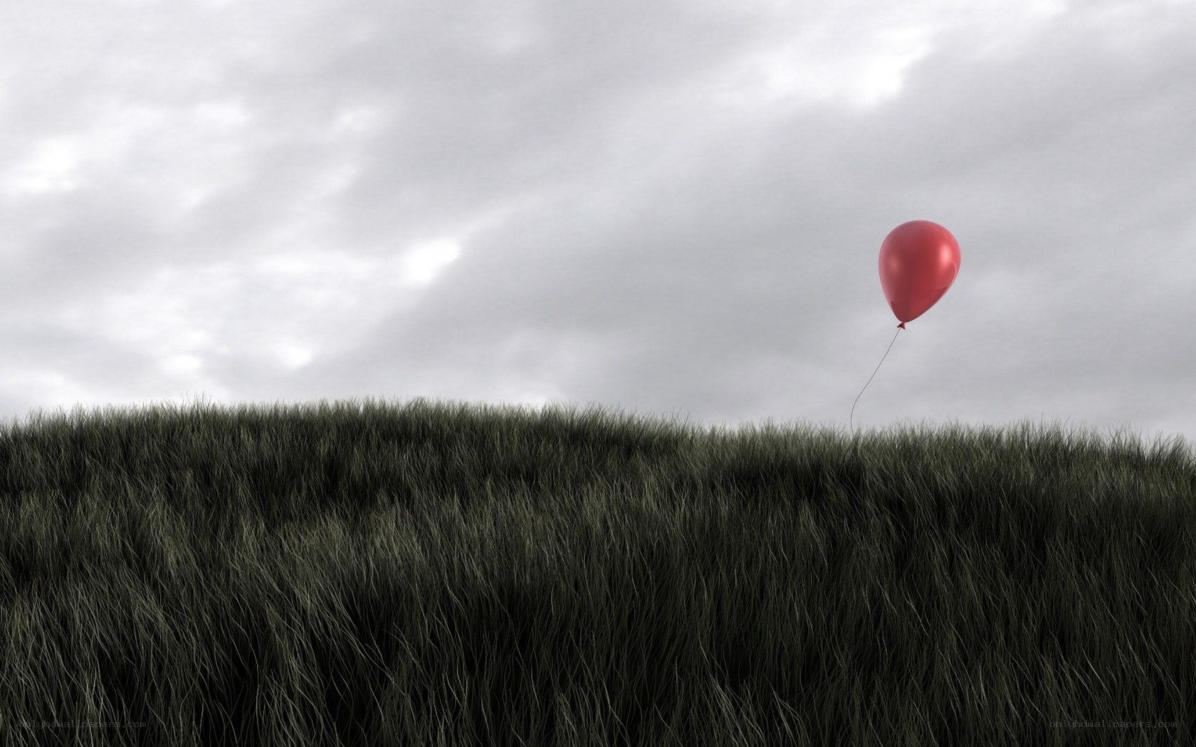 Red balloon over grassy hill