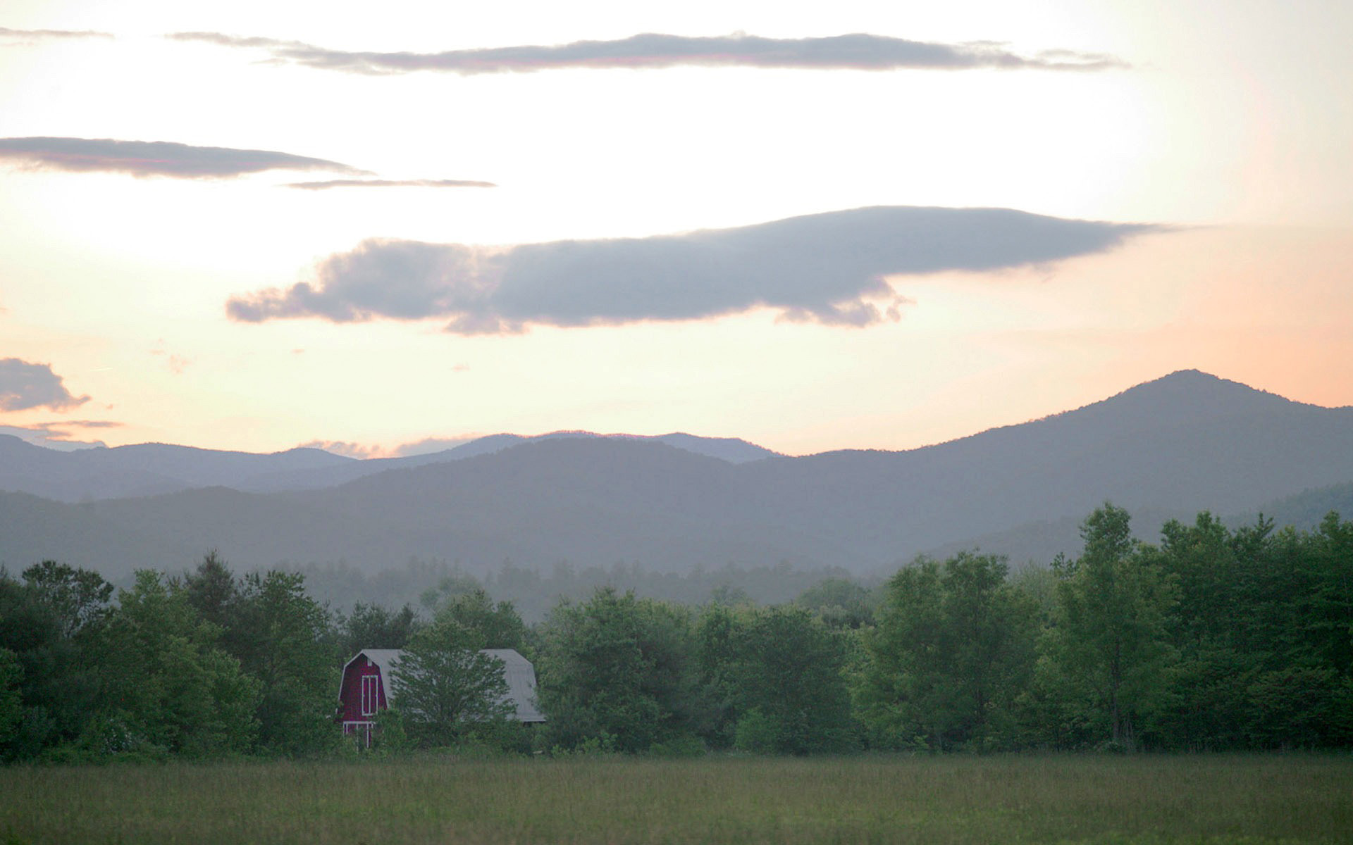 Red barn at sunset with mountains