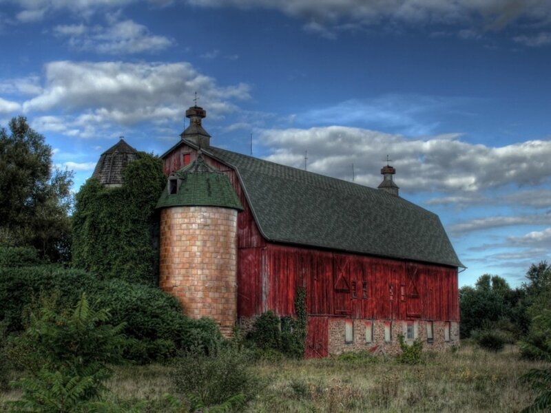 Red barn with silo under blue sky