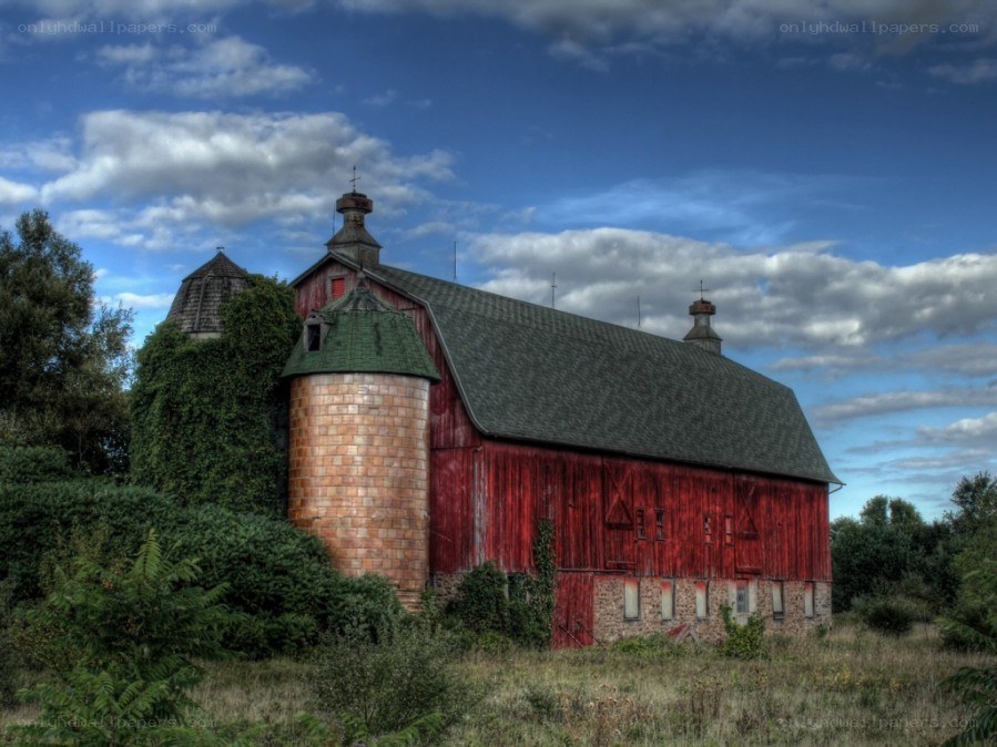Red barn with silo under blue sky