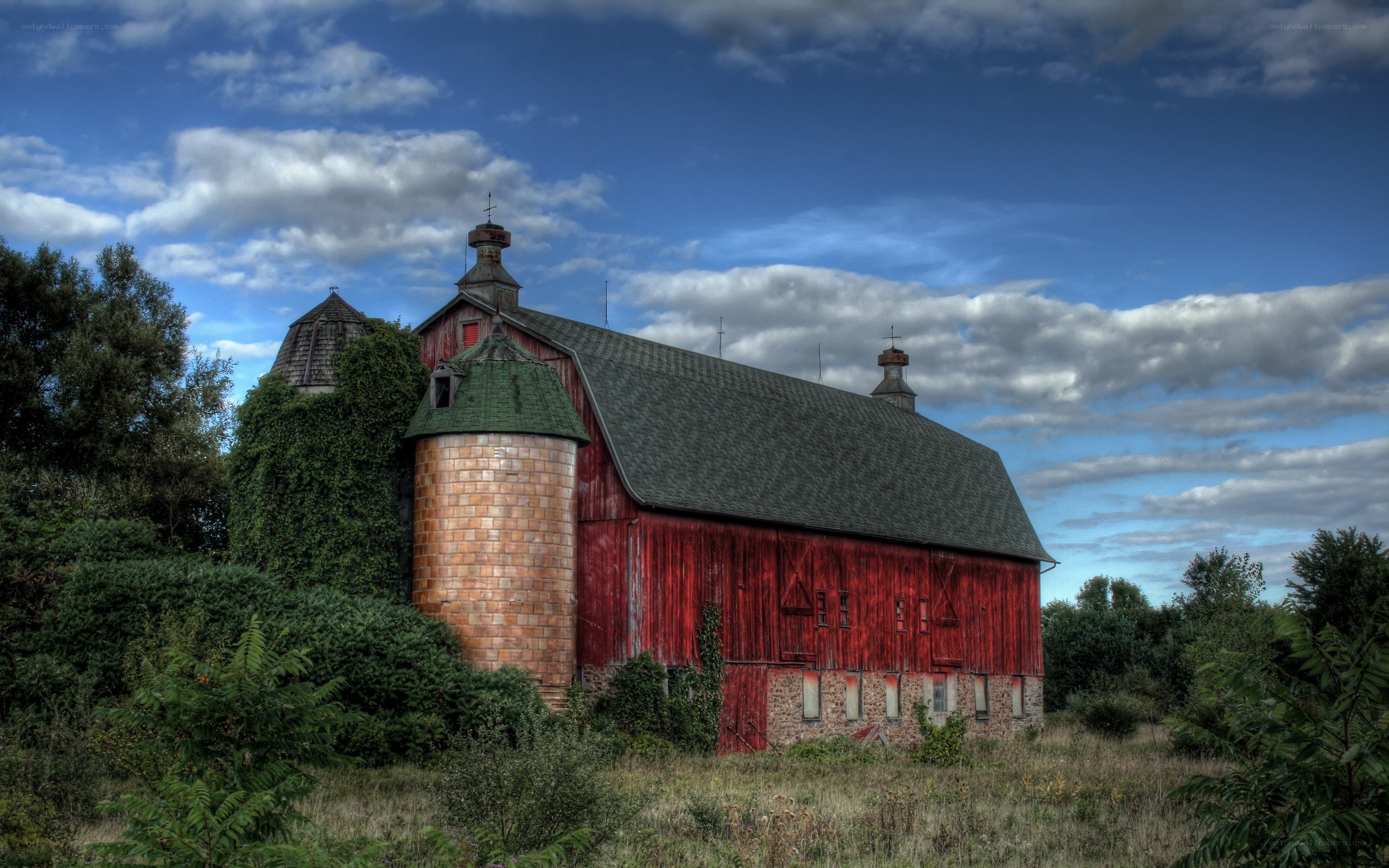 Red barn with silo under cloudy sky