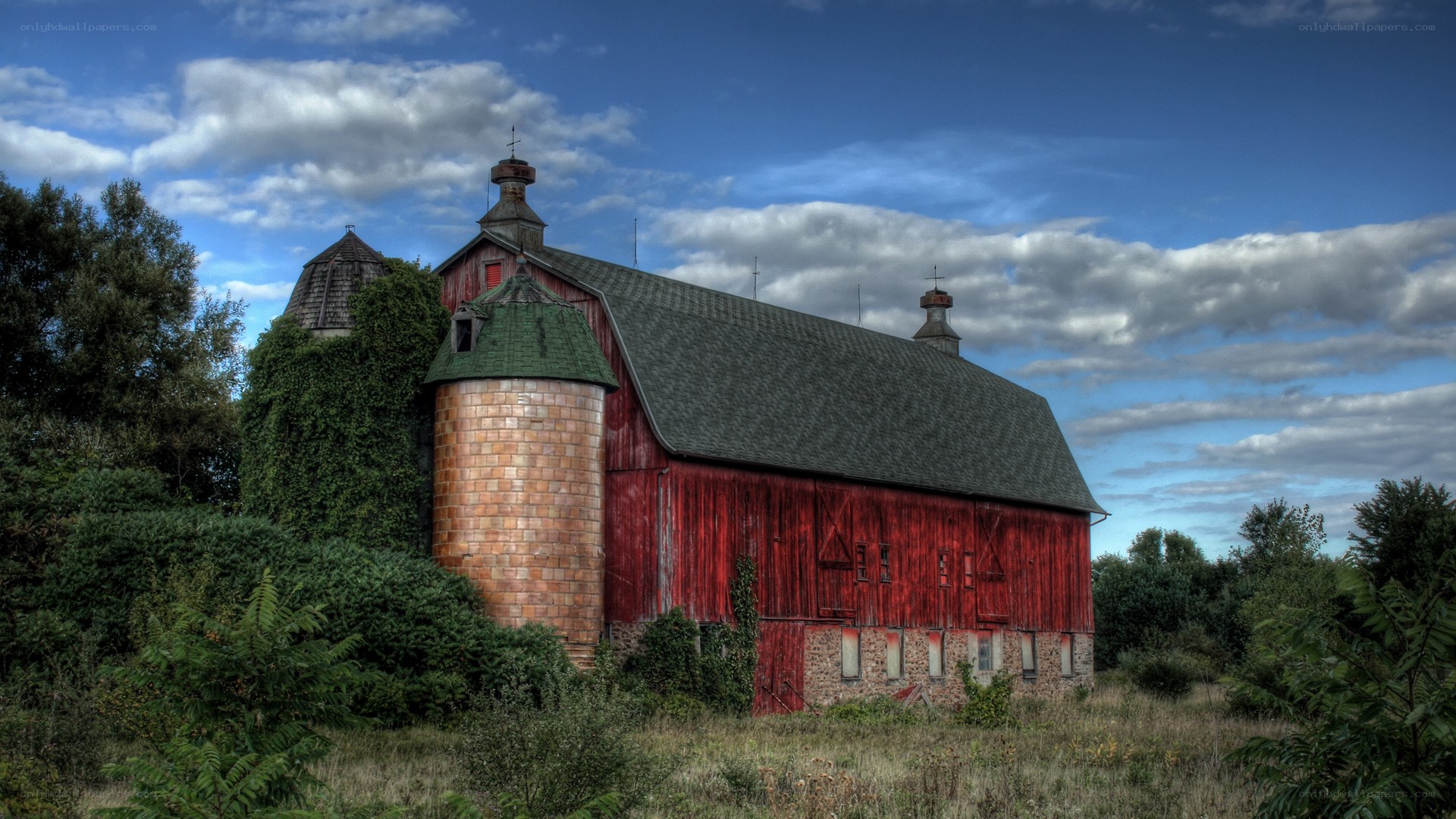 Red barn with silo under cloudy sky