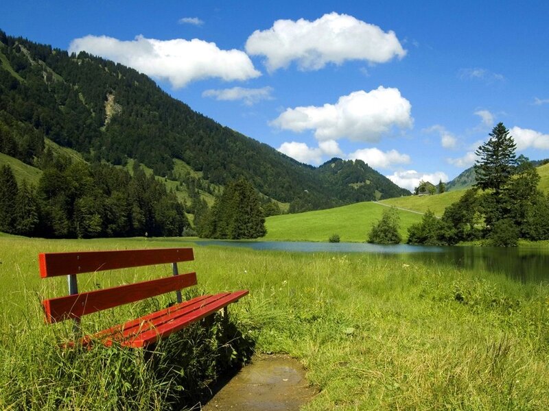 Red bench by a mountain lake