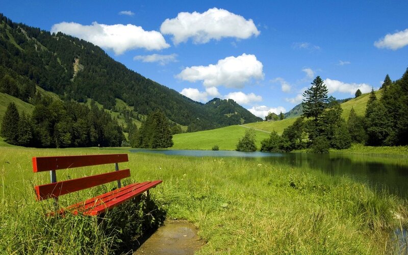 Red bench by a mountain lake