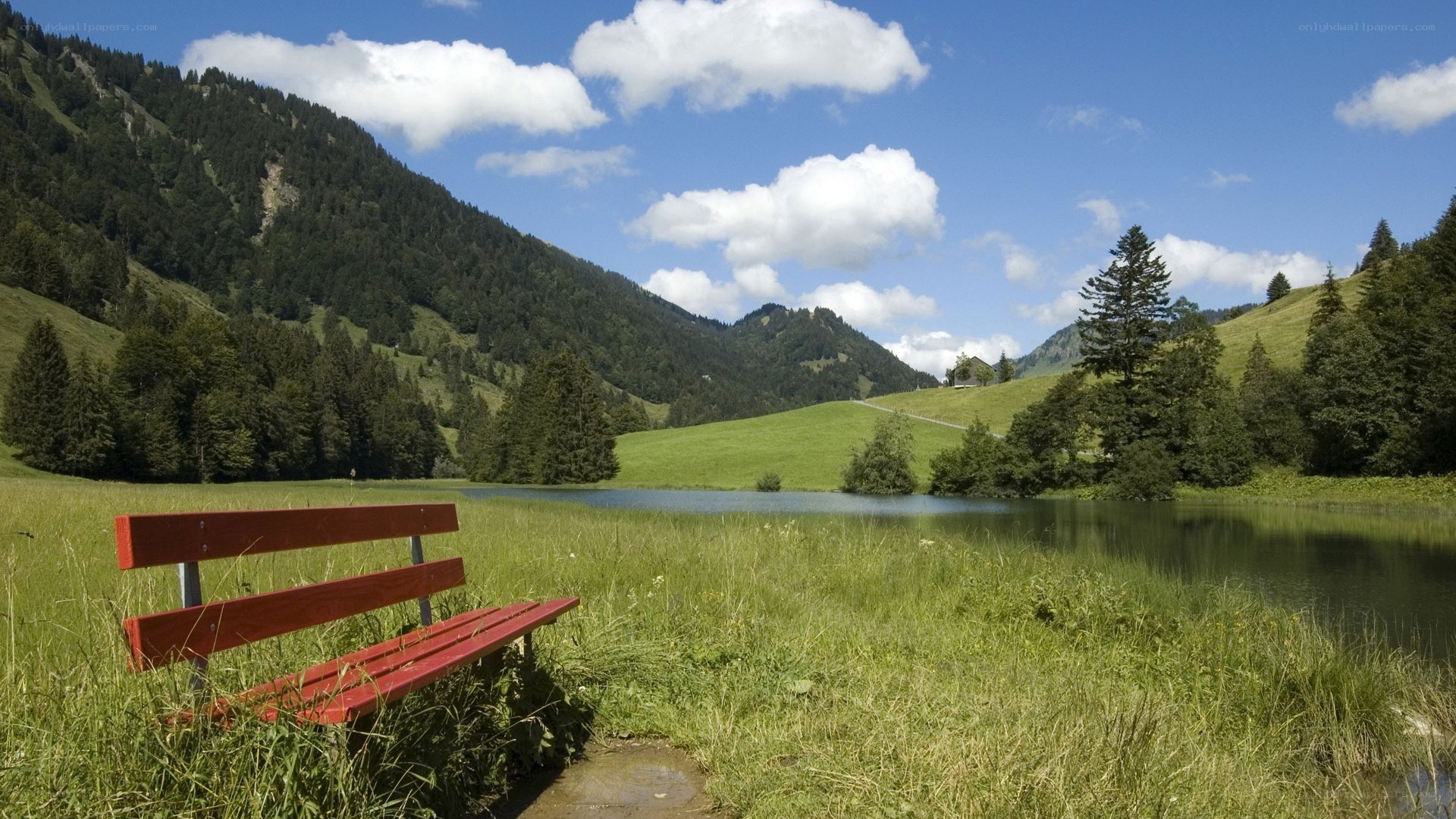 Red bench by a mountain lake