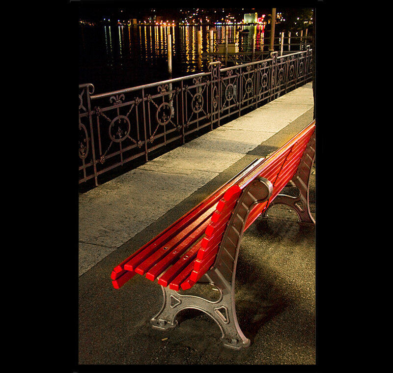 Red bench by the water at night