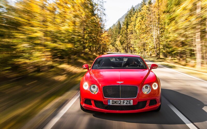 Red Bentley driving on a forest road