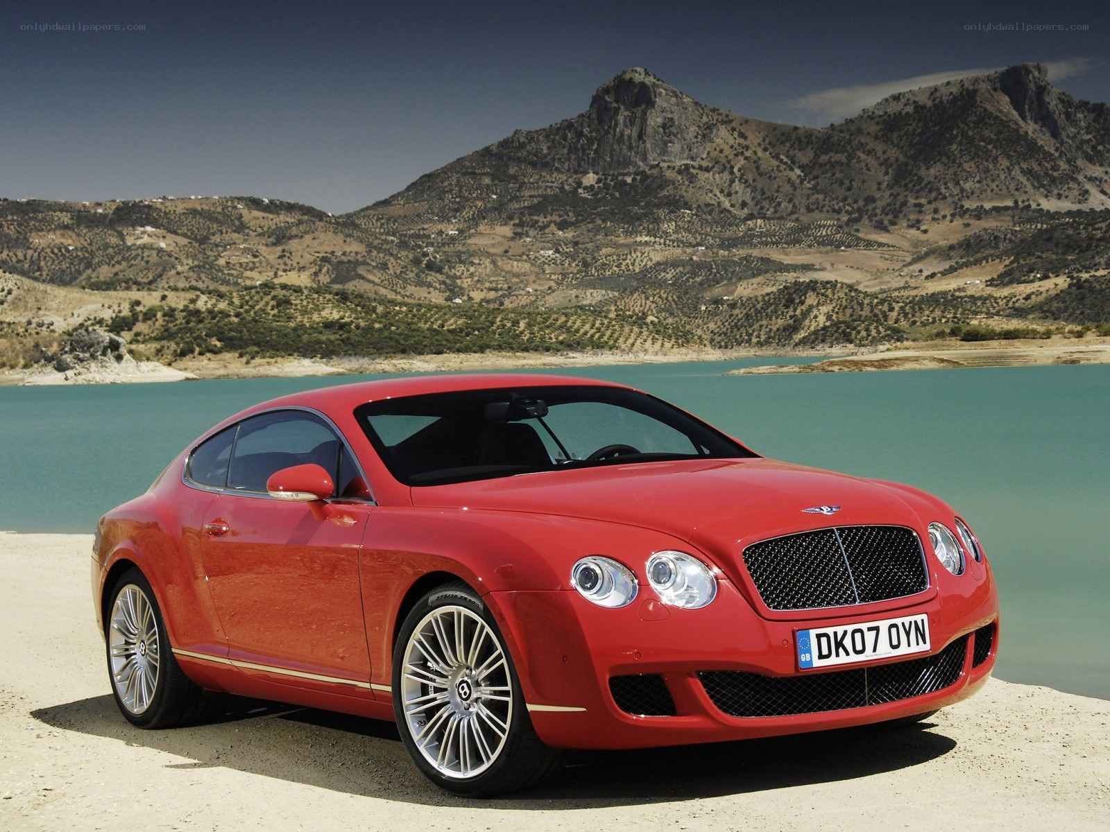 Red Bentley parked by a lake