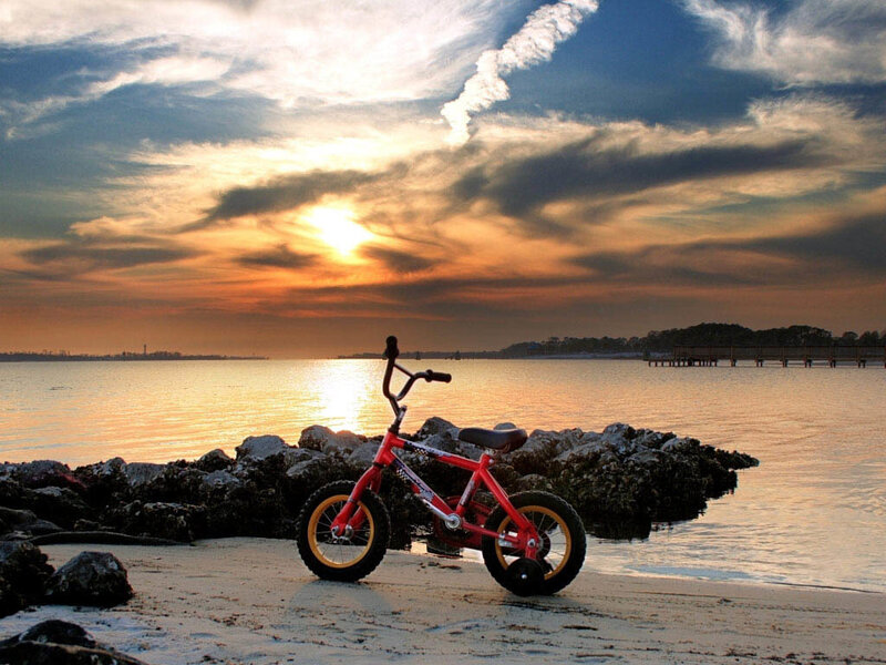 Red bike on beach at sunset