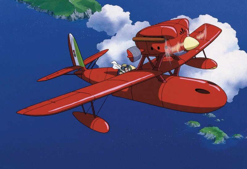 Red biplane flying over ocean