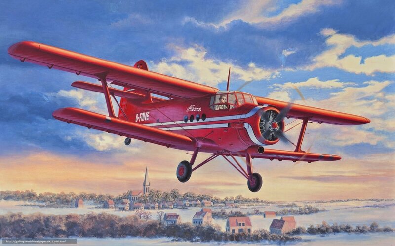Red biplane flying over village