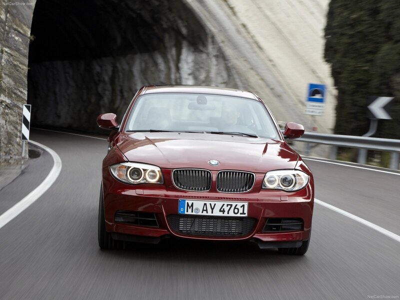 Red BMW 1-Series driving on a road