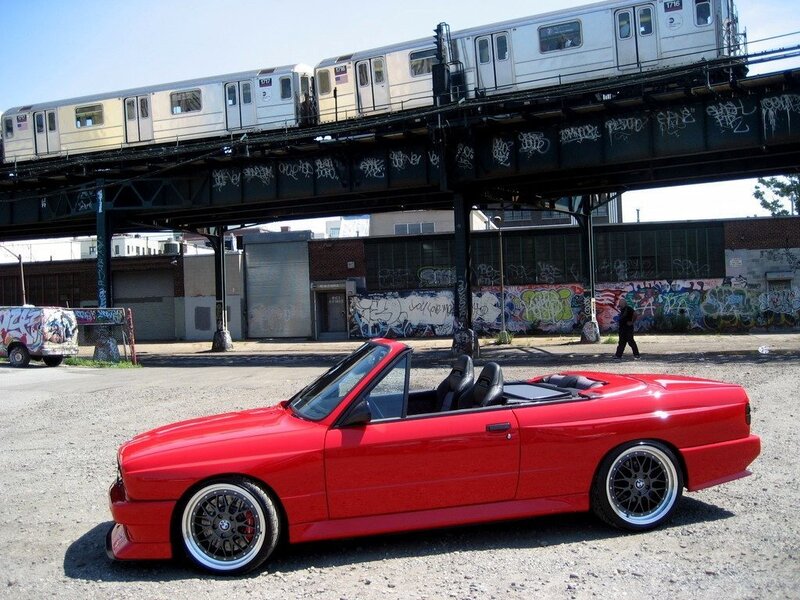 Red BMW convertible under train tracks