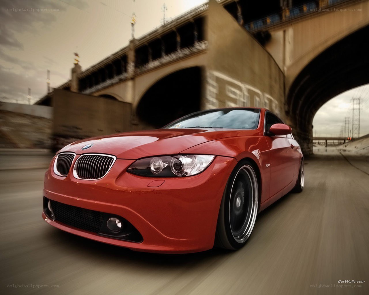 Red BMW driving under bridge