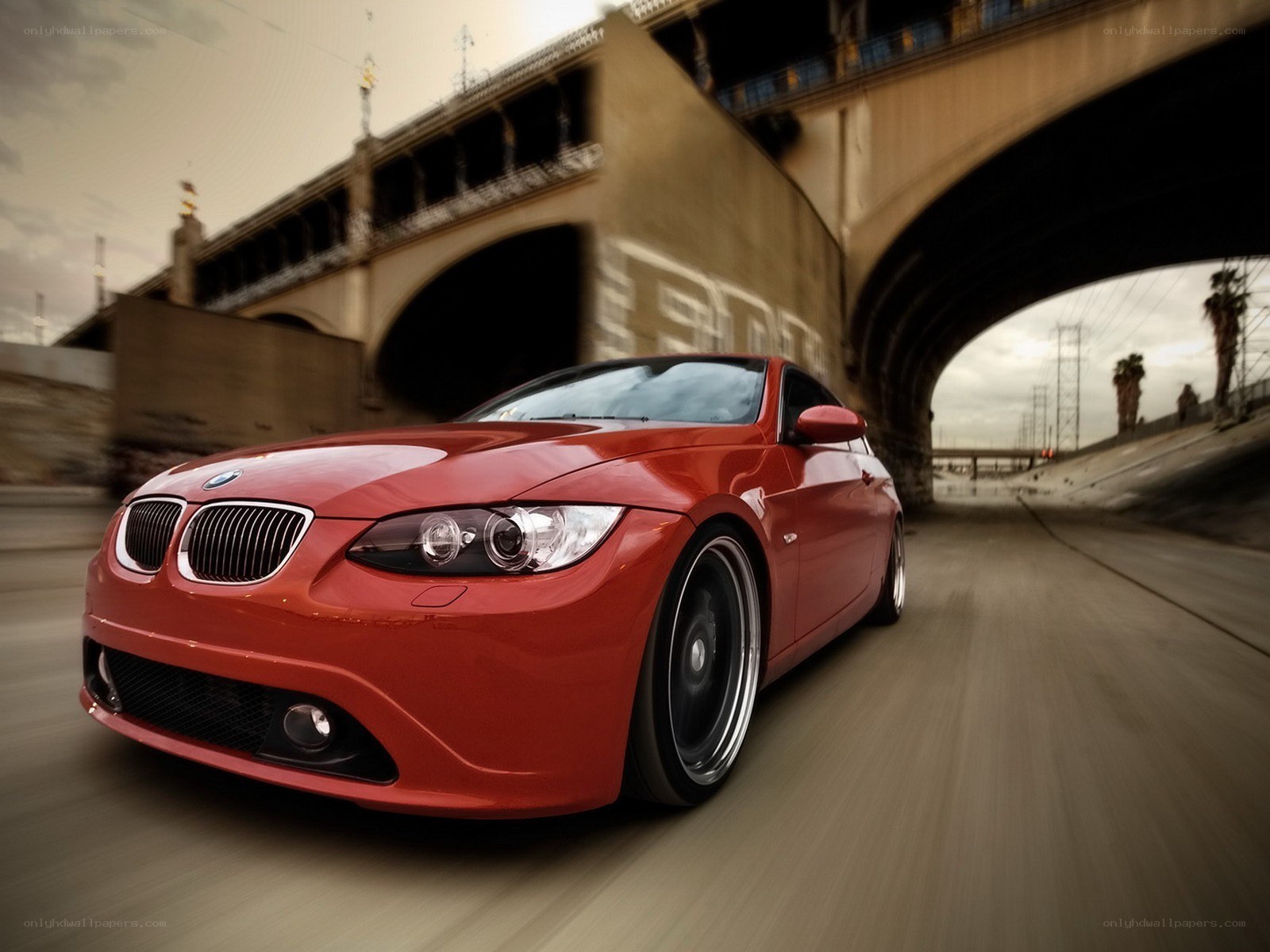Red BMW driving under bridge
