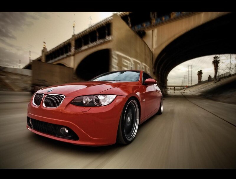 red bmw driving under bridge