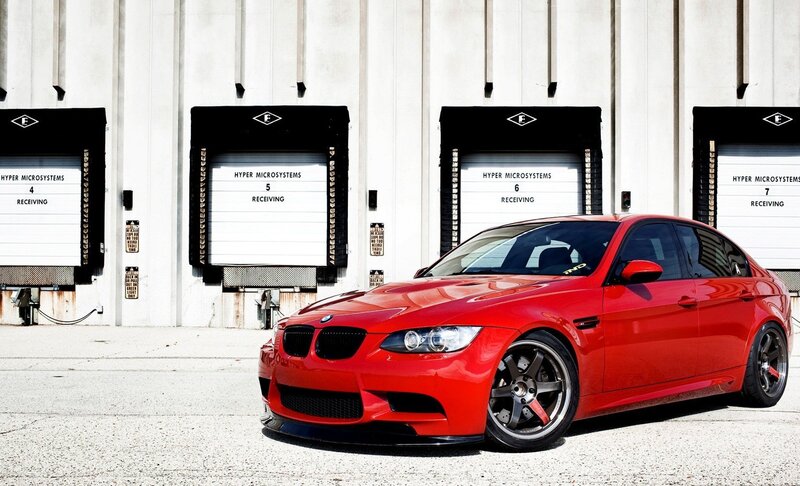 Red BMW M3 in front of warehouse