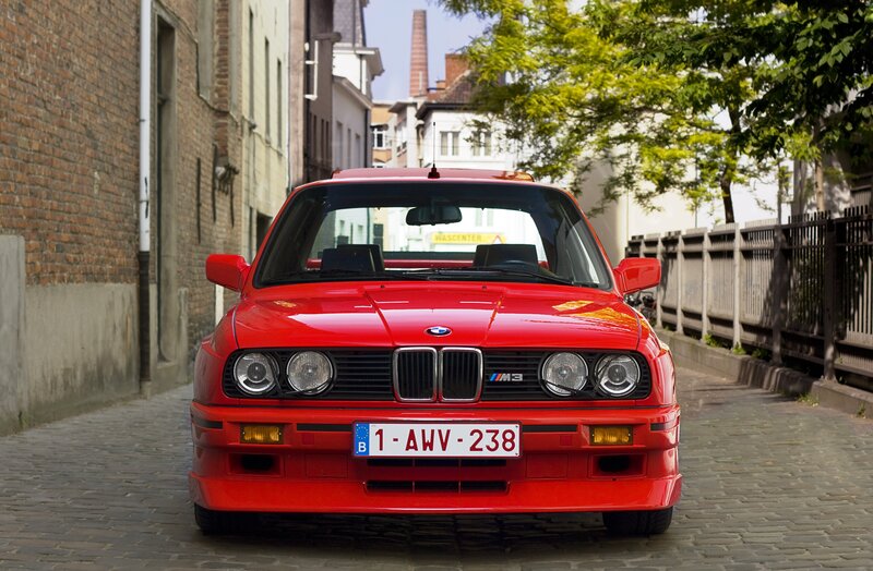 Red BMW M3 on cobblestone street