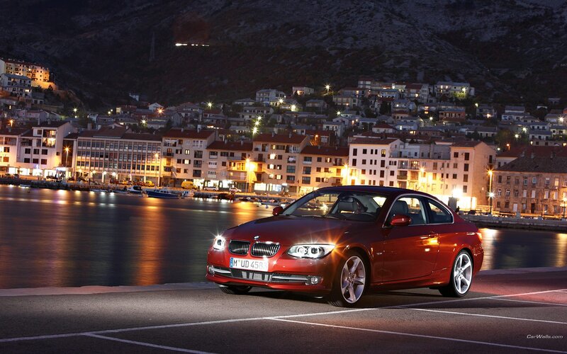 Red BMW parked by a harbor at night