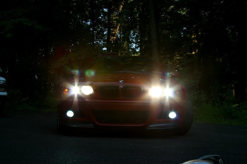 Red BMW with headlights on