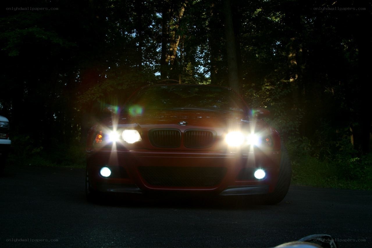 Red BMW with headlights on