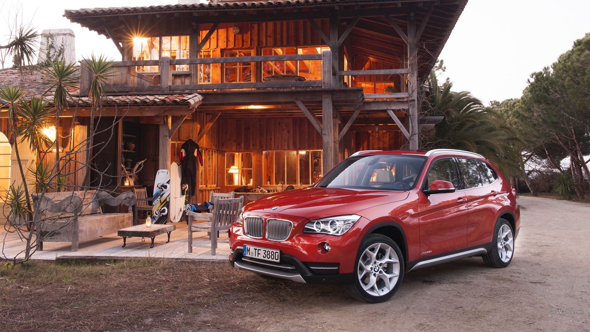 Red BMW X1 parked by a cabin
