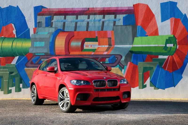 Red BMW X6 M in front of mural