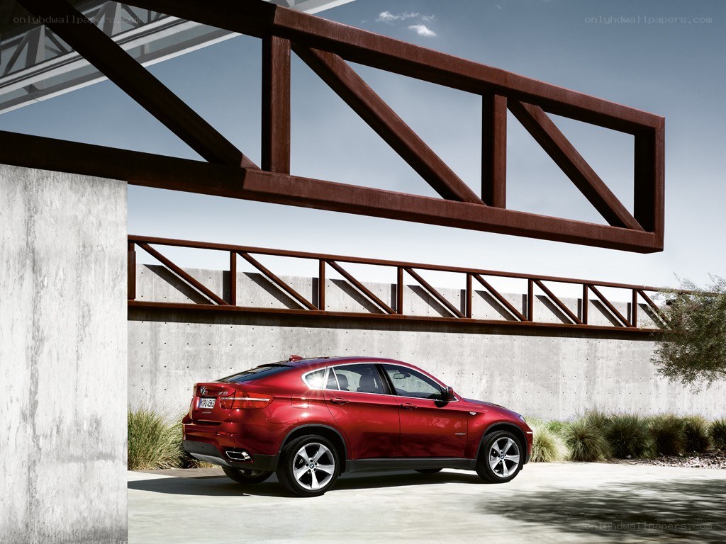 Red BMW X6 under a bridge