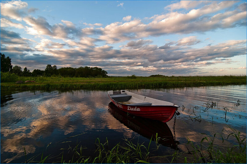 Red boat on calm water at sunset